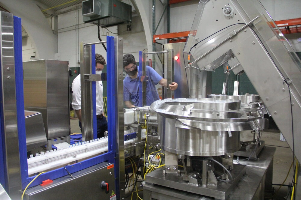 Photo of two workers around the COVID-19 test kit machine.