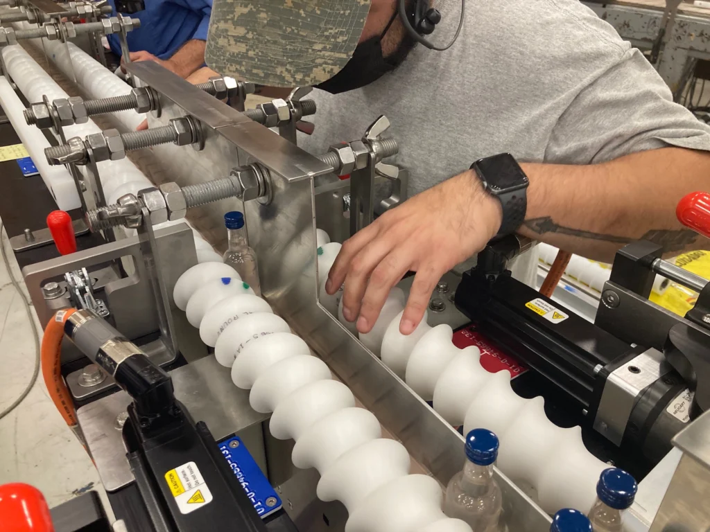 Man testing bottles moving down a line of timing screws