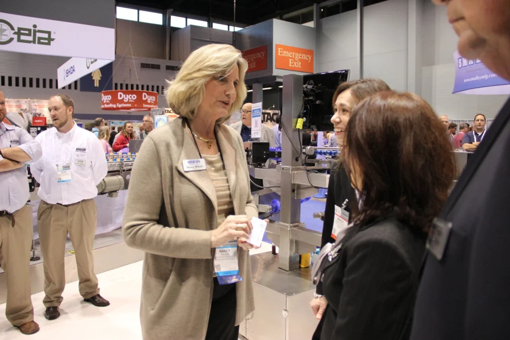 Photo of Nancy Wilson talking to customers in a trade show booth.