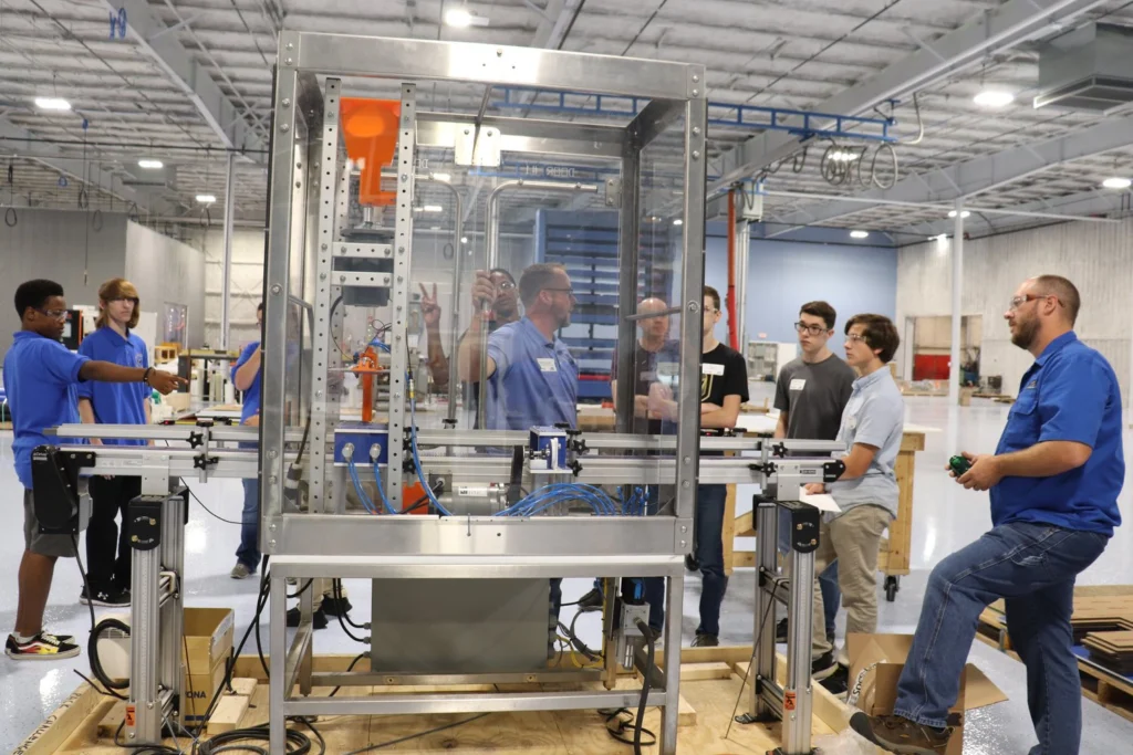 A group of students gather around a machine they are building in the Morrison facility.